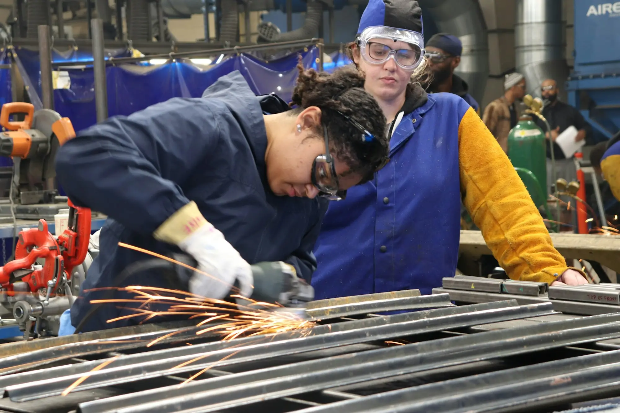 Trainer showing a new staff member how to work metal in a workshop